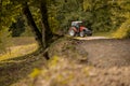 Red tractor approaching the camera on a small gravel road in the forest, manouvering around tight corners and bends. Forest Royalty Free Stock Photo