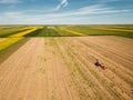 Red Tractor baling hay, sunflower fields and blue sky in the background Royalty Free Stock Photo