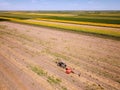 Red Tractor baling hay, sunflower fields and blue sky in the background Royalty Free Stock Photo