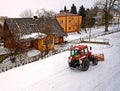 A red tractor clears the road from the snow. Winter cleaning of the street. Community service. Weather. Winter village. Snowblower Royalty Free Stock Photo