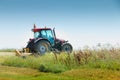 red tractor equipped with a large mower, cuts the grass in a meadow