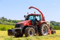 Red tractor in the field, agricultural machinery harvesting. Feed for cows for the winter. Royalty Free Stock Photo