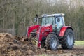 Red tractor with front loader in front of a manure heap Royalty Free Stock Photo