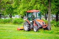 Red tractor and lawn mower, shears lawns in the alleys in the park. Royalty Free Stock Photo