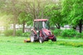 Red tractor and lawn mower, shears lawns in the alleys in the park. Royalty Free Stock Photo