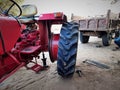 red tractor lifted up on iron chassis jack and punctured tyre opened for repair