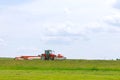 A red tractor mows the grass on a farmer's field. Two mowers will mow a large area of the field. Royalty Free Stock Photo
