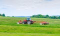 A red tractor mows the grass on a farmer's field. Two mowers will mow a large area of the field. Royalty Free Stock Photo