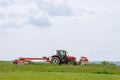 A red tractor mows the grass on a farmer's field. Two mowers will mow a large area of the field. Royalty Free Stock Photo