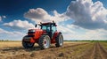 Red tractor plowing cereal field with sky with clouds