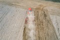 Red tractor plowing farm field aerial view looking down from above through clouds. Drone photo cultivation machine Royalty Free Stock Photo