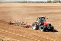 A red tractor plowing a farm field. Royalty Free Stock Photo