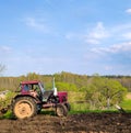 A red tractor plows a field in spring Royalty Free Stock Photo