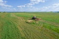 A red tractor rakes the mown grass for drying. Modern equipment on the field. Royalty Free Stock Photo