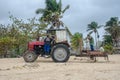 Red Tractor on resort beach clearing weed