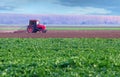 Red tractor working on thre agricultural field