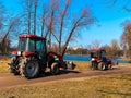 Red tractors trucks in spring city park. Cleaning. Early spring. Works. Sunny spring day. Royalty Free Stock Photo