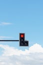 Red traffic light against blue sky background