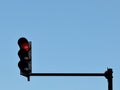 Red traffic light installed on a pole above a roadway, against a blue sky Royalty Free Stock Photo