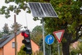 Red traffic light next to a solar system, a right turn sign and a caution road sign in Germany. Remote power supply in traffic. Royalty Free Stock Photo