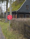 Red traffic sign with czech text: Pozor deti - Attention children in front of wooden timbered house cotttage with moss