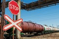 Red traffic STOP sign in front of the train moving in the background passing rail cisterns Royalty Free Stock Photo