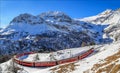 Red train from Rhaetian Railway is passing the train tracks with tight 180ÃÂ° curve