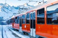 Red train running on rack railway through snowy Swiss Alps