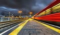 Red train speeding through station platform at dusk Royalty Free Stock Photo
