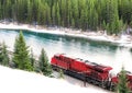 Red train traveling along railroad track through winter forest w Royalty Free Stock Photo