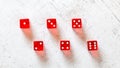 Red translucent craps dices on white board, showing all numbers from 1 to 6 photographed from above