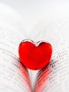 Red transparent glass heart lay in a book