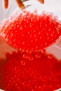 Red transparent hydrogel balls falling into a vase