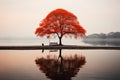 a red tree is sitting on the edge of a lake