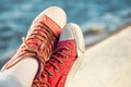 Red trendy sneakers on girl and seascape as background