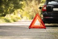 Red triangle, red emergency stop sign and black car with technical problems in the blurred background. Emergency stop of the car