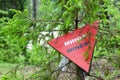 Red triangle mine warning sign in the forest Royalty Free Stock Photo