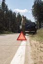 Red triangle sign on side road after car break and driver speaking on mobile phone, calling auto repair service Royalty Free Stock Photo