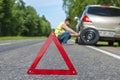 Red triangle warning sign and man changing the tire Royalty Free Stock Photo