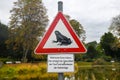 Red triangular street sign with frog meaning `amphibian migratio` and sign warning about not feeding ducks as it harms them in Ger