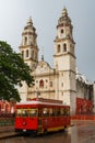 Red trolley in front of the towering Cathedral of Campeche