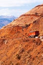 Red truck driving on a mountain road on winter dusk, fantastic landscape of red mountain ridge and snow mountains backdrop Royalty Free Stock Photo