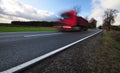 Red truck in a motion on tarmac road