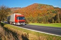 Red truck on the road under the wooded mountain of colorful autumn colors Royalty Free Stock Photo