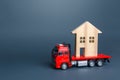 Red truck transports the residence house. Delivery services to another house. A moving company. Transportation of real estate