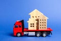 Red truck transports wooden houses. Concept of transportation and cargo shipping, moving company. Construction of new houses