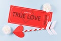 Red `True Love` ticket and cupid arrow on blue background for Valentine`s day