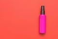 A red tube with a spray bottle with lotion on a red background