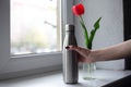 Red tulip with steel bottle on the background of the window Royalty Free Stock Photo