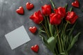 Red tulips with a blank greetings card mock-up with space for romantic love text and hearts on concrete background Royalty Free Stock Photo